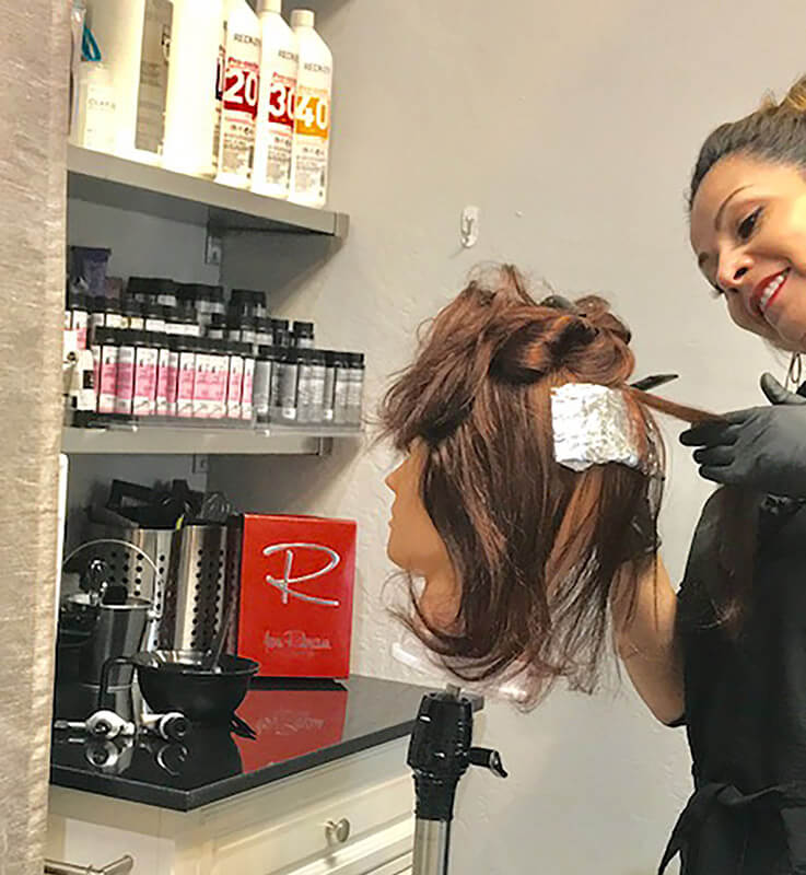 Experienced stylist coloring the hair for a more natural looking wig.