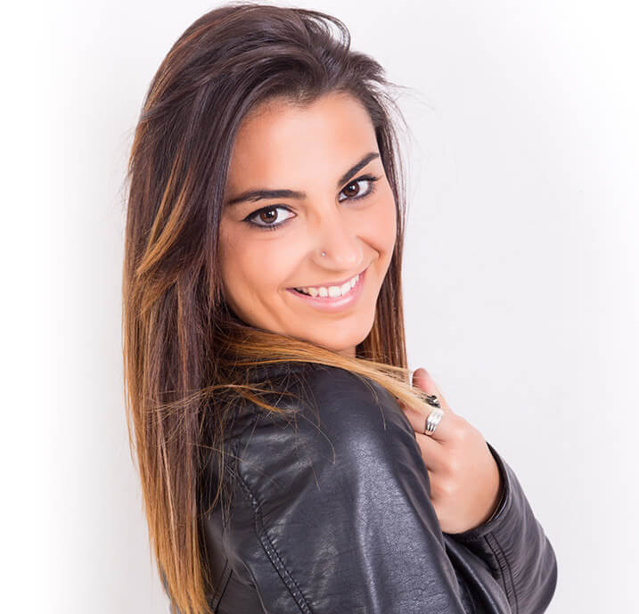 Woman standing confidently after having hair extensions placed in her hair giving her a fuller look.